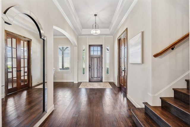 entryway with an inviting chandelier, french doors, a raised ceiling, ornamental molding, and dark hardwood / wood-style flooring