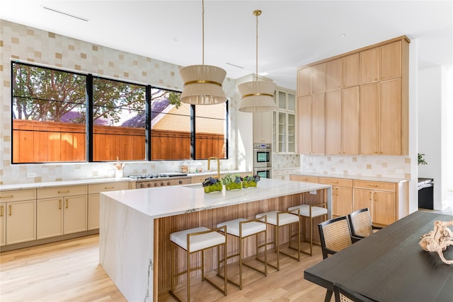 kitchen featuring a kitchen bar, tasteful backsplash, a center island, and light wood-type flooring