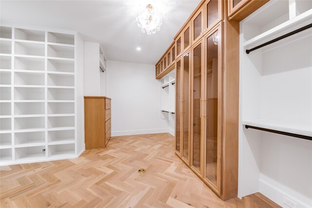 walk in closet featuring light parquet floors and a chandelier