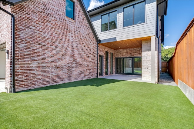 back of house featuring brick siding, a lawn, and a fenced backyard