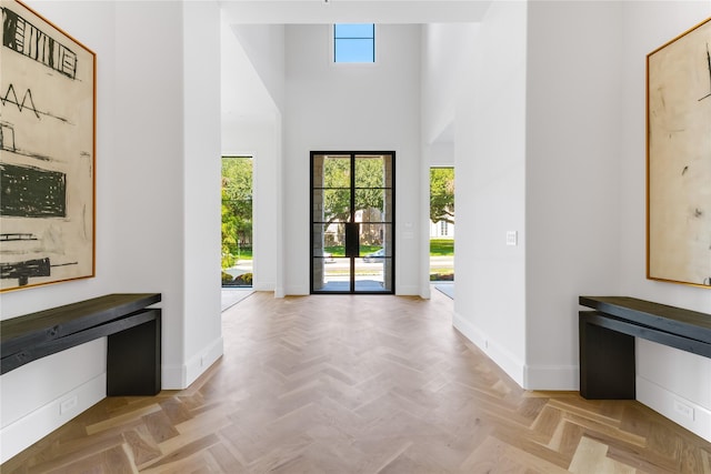 foyer entrance with a towering ceiling and light parquet floors