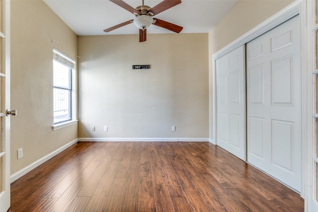 unfurnished bedroom featuring dark hardwood / wood-style floors, ceiling fan, and a closet