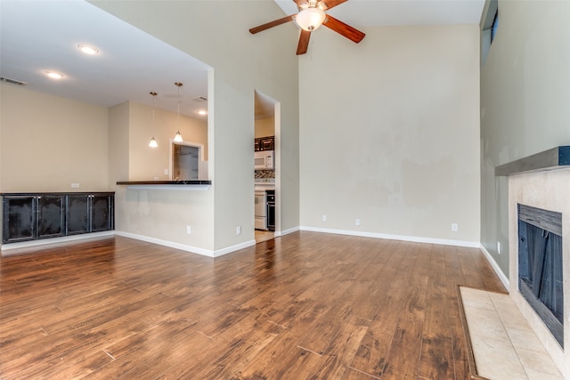 unfurnished living room with hardwood / wood-style flooring, ceiling fan, a fireplace, and vaulted ceiling