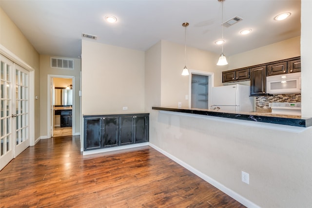 kitchen featuring tasteful backsplash, dark hardwood / wood-style flooring, decorative light fixtures, and white appliances