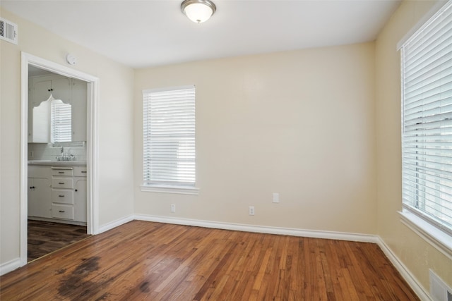 unfurnished bedroom with dark wood-type flooring and ensuite bath