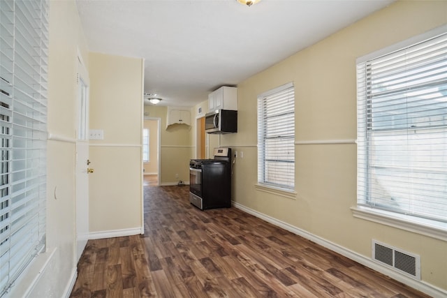 interior space with white cabinetry, stainless steel appliances, and dark hardwood / wood-style flooring