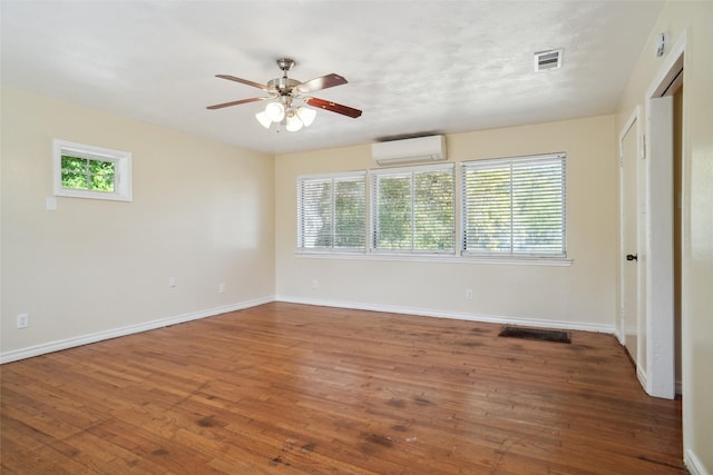 unfurnished room featuring a wall unit AC, dark hardwood / wood-style floors, and ceiling fan