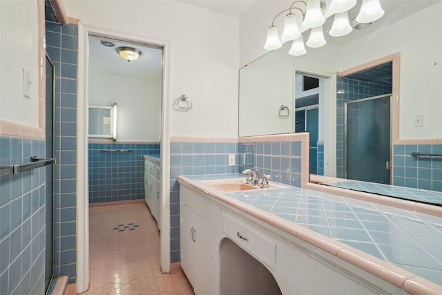 bathroom with vanity, tile walls, an enclosed shower, and tile patterned flooring