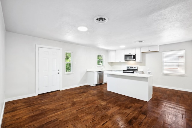 kitchen with a center island, sink, dark hardwood / wood-style floors, white cabinetry, and stainless steel appliances