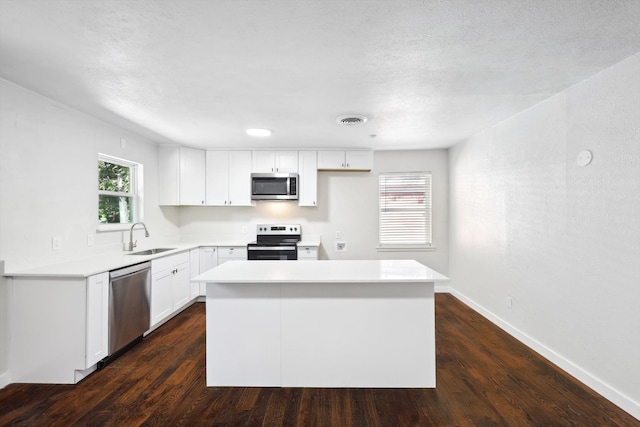 kitchen featuring white cabinets, sink, dark hardwood / wood-style floors, a kitchen island, and stainless steel appliances