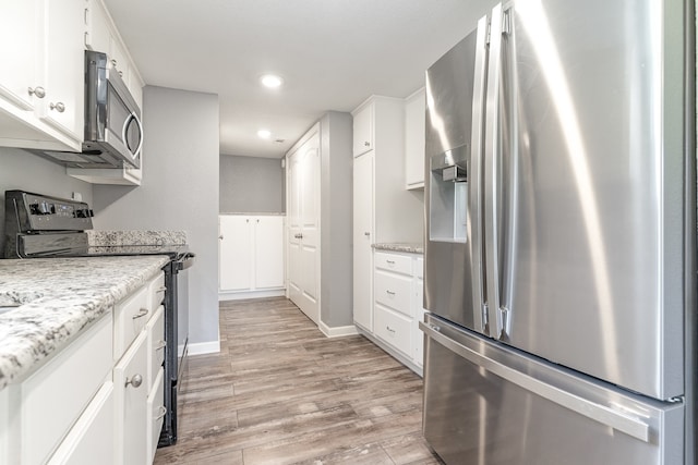 kitchen featuring recessed lighting, light wood-style flooring, appliances with stainless steel finishes, white cabinetry, and baseboards