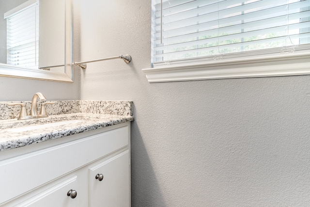 bathroom featuring a textured wall, vanity, and a wealth of natural light