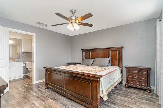 bedroom with light wood finished floors, visible vents, connected bathroom, ceiling fan, and baseboards