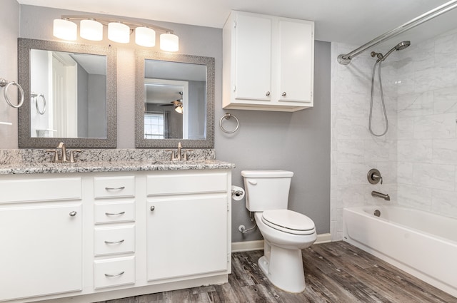 full bathroom with toilet, double vanity, a sink, and wood finished floors