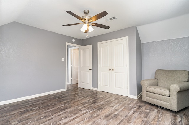 living area with visible vents, ceiling fan, vaulted ceiling, wood finished floors, and baseboards