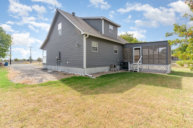 rear view of house with a sunroom, a yard, and central AC unit