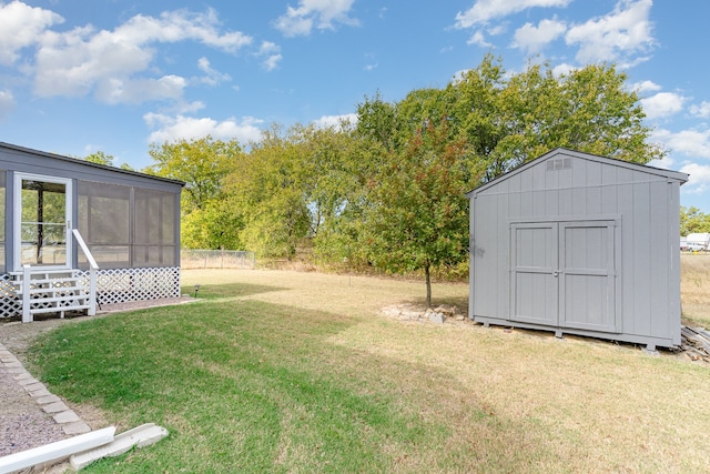 view of yard with an outbuilding, a shed, and a sunroom