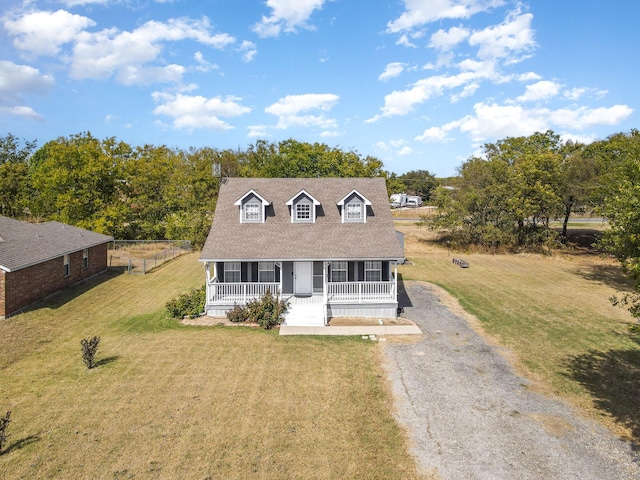 new england style home with driveway, a porch, roof with shingles, and a front yard