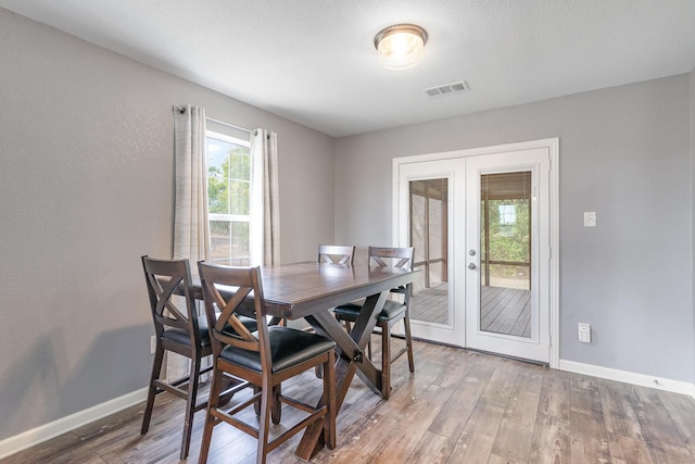 dining space with french doors, visible vents, baseboards, and wood finished floors