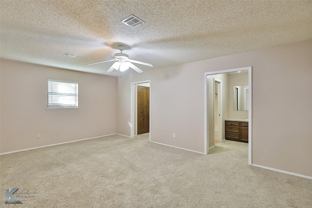 unfurnished bedroom featuring light colored carpet, ceiling fan, and ensuite bath