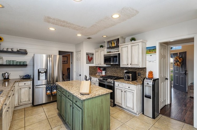 kitchen with light stone counters, a kitchen island, appliances with stainless steel finishes, green cabinets, and light hardwood / wood-style flooring