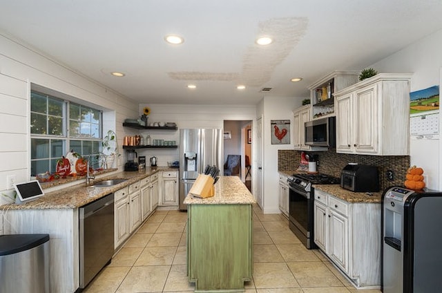 kitchen with stainless steel appliances, sink, light stone counters, a center island, and decorative backsplash