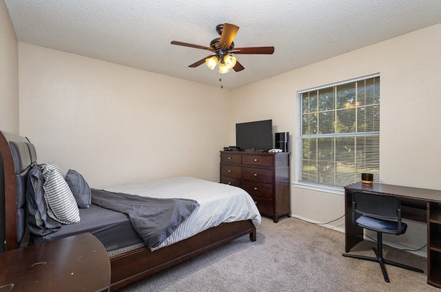 carpeted bedroom featuring ceiling fan and a textured ceiling