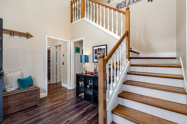 staircase featuring hardwood / wood-style floors and a towering ceiling