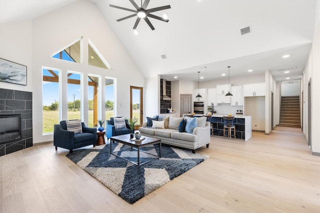 1561 Dixie Estates Way, Whitesboro, TX 76273 - living area featuring light wood-style flooring, high vaulted ceiling, a ceiling fan, a tile fireplace, and stairway