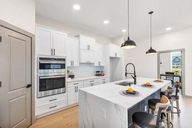 1561 Dixie Estates Way, Whitesboro, TX 76273 - kitchen with double oven, a sink, backsplash, white cabinets, and a center island with sink