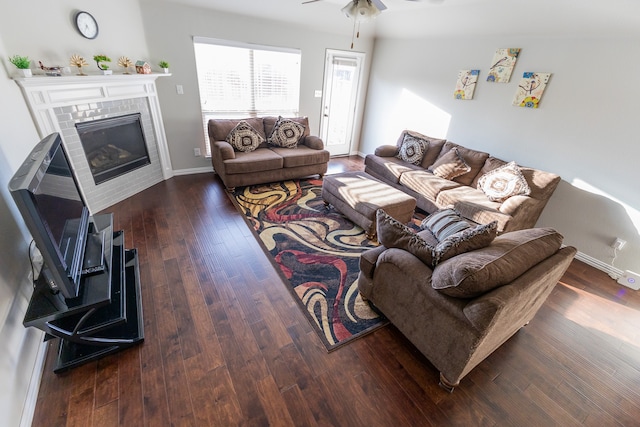 living room featuring ceiling fan, dark wood-type flooring, and a brick fireplace