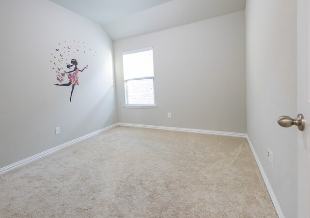 empty room with vaulted ceiling and light colored carpet