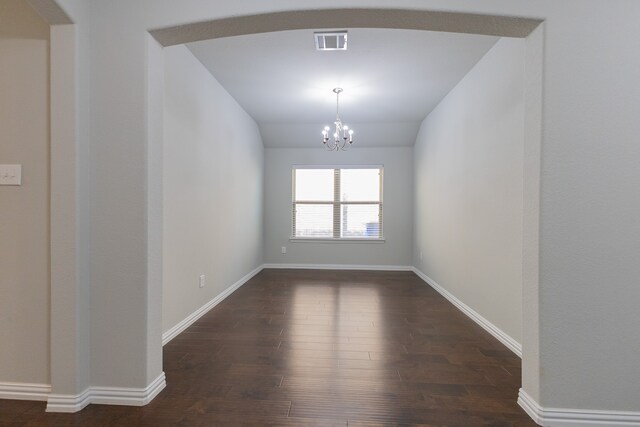 empty room with a notable chandelier and dark hardwood / wood-style floors