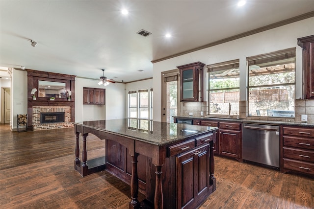 kitchen featuring dishwasher, dark wood-type flooring, a center island, a kitchen bar, and a brick fireplace