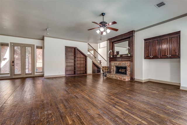 unfurnished living room featuring a brick fireplace, ceiling fan, crown molding, and dark hardwood / wood-style flooring