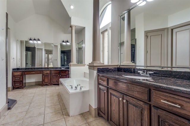 bathroom with tile patterned floors, a bathtub, decorative columns, vaulted ceiling, and vanity