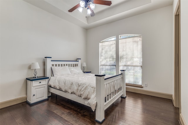 bedroom featuring dark wood-type flooring, ceiling fan, and a raised ceiling