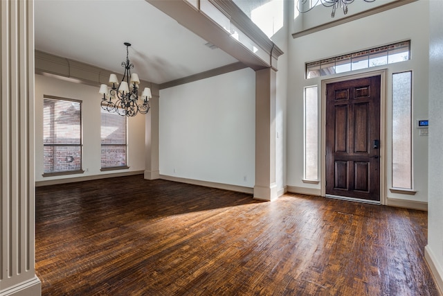 entrance foyer featuring an inviting chandelier, ornamental molding, a healthy amount of sunlight, and dark hardwood / wood-style flooring