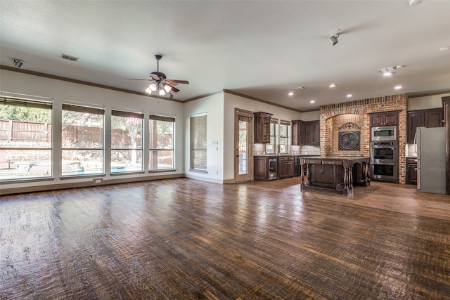 unfurnished living room featuring ceiling fan and crown molding