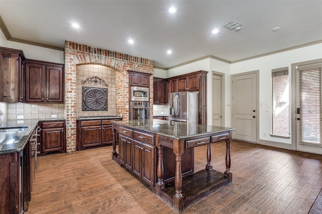 kitchen with dark brown cabinets, hardwood / wood-style flooring, appliances with stainless steel finishes, and a center island