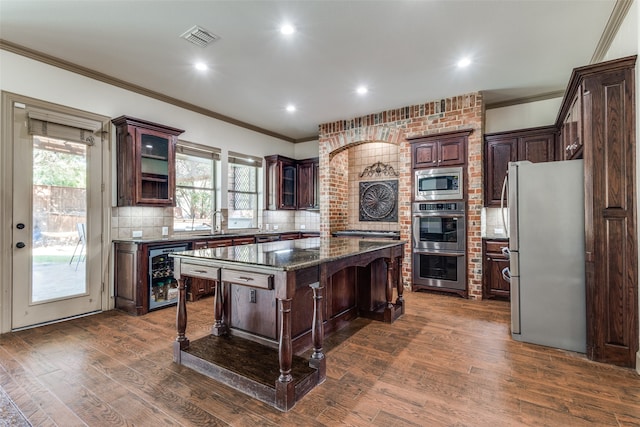 kitchen featuring a kitchen island, a breakfast bar area, dark wood-type flooring, stainless steel appliances, and plenty of natural light