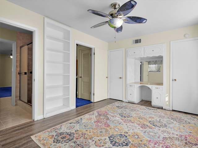 bedroom with built in desk, dark hardwood / wood-style floors, and ceiling fan