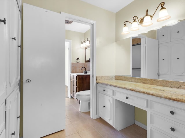 bathroom featuring vanity, toilet, tile patterned floors, and backsplash