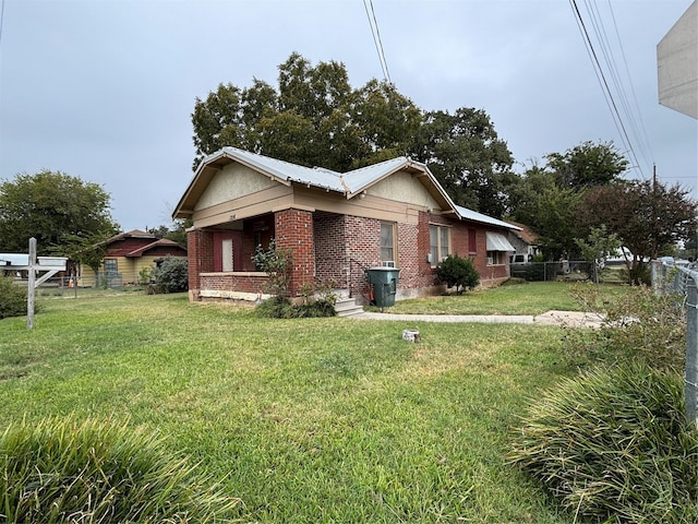 view of side of home featuring a yard, brick siding, and fence