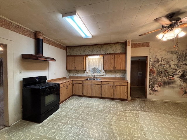 kitchen featuring ceiling fan, sink, wall chimney range hood, and black gas range