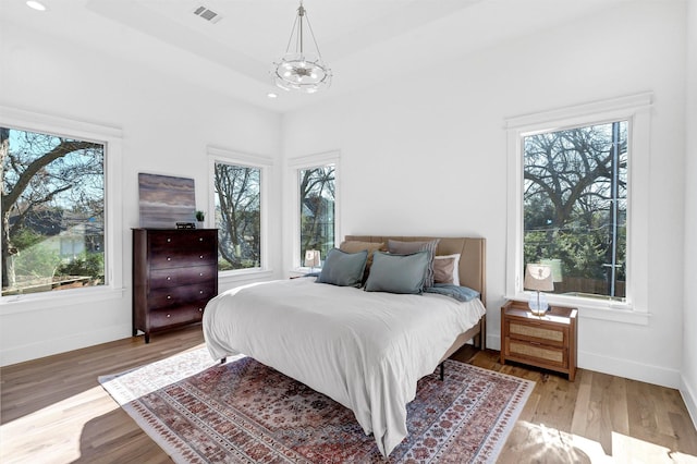 bedroom featuring multiple windows, a chandelier, and hardwood / wood-style flooring