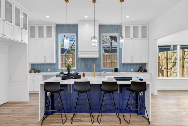 kitchen featuring sink, white cabinetry, hanging light fixtures, and a kitchen island with sink