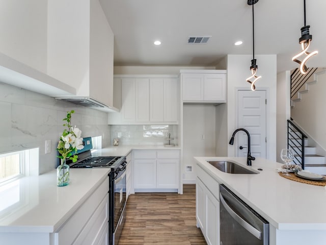 kitchen featuring hardwood / wood-style floors, white cabinetry, stainless steel appliances, sink, and decorative light fixtures