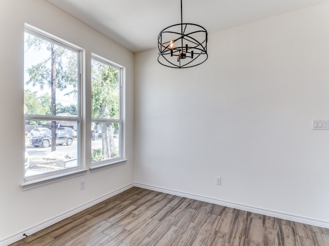 spare room with an inviting chandelier and light wood-type flooring