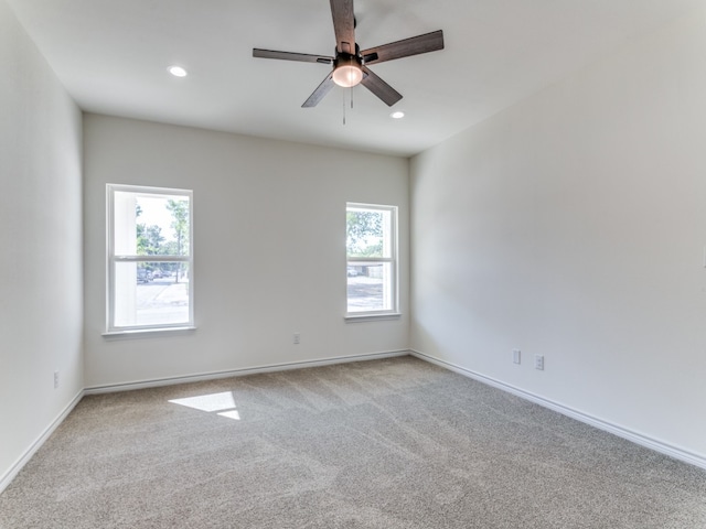 carpeted spare room with ceiling fan and plenty of natural light